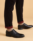 Man with black jeans and knit socks wearing the Whiddon Apron dress shoe. 