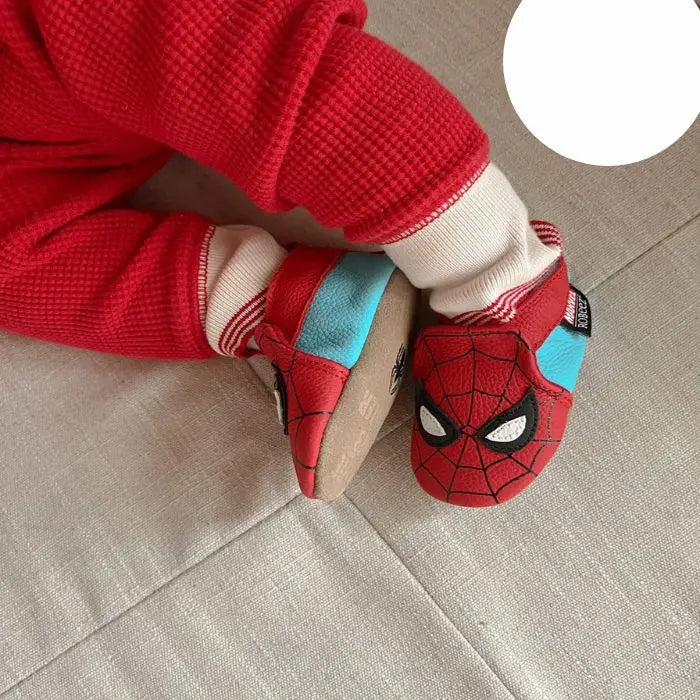 Baby wearing red and blue Spiderman baby leather shoes.