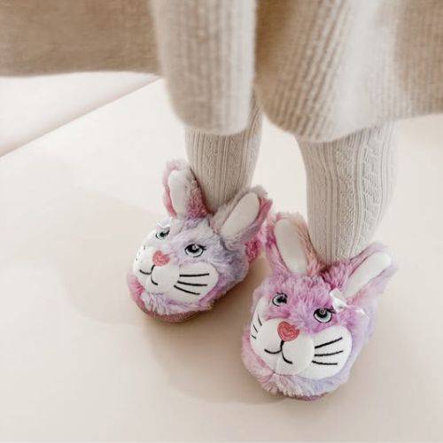 Child wearing pink and purple fluffy bunny slippers with adorable face design.