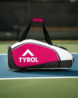 Red and white Tyrol sports bag with multiple compartments on a tennis court surface.