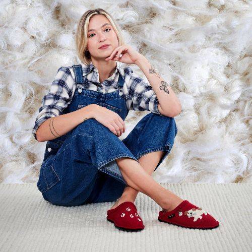 Model sitting on a carpet wearing the Fido slippers. 