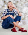 Model sitting on a carpet wearing the Fido slippers. 