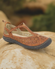 Brown Mary-Jane Flat by on rocky surface against a blurred natural background.