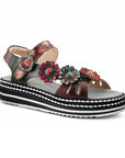 Black leather sandals with a multicoloured purple upper, floral buttons, and a black and white layered platform outsole. 