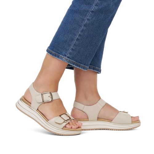 Person wearing beige Remonte backstrap sandals and cropped blue jeans.