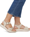 Person wearing beige Remonte backstrap sandals and cropped blue jeans.