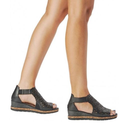 Person wearing black wedge sandal with floral cut-outs.