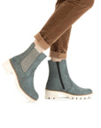 Women's legs in brown khaki pants wearing Rieker blue Chelsea boot with platform lugged white outsole.