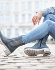 Women sitting on cobblestone in blue jeans wearing blue Chelsea boot with platform lugged white outsole.