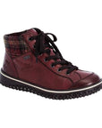 A Rieker red leather sneaker boot with flat black laces, red plaid fabric heel cuff, circle logo on heel,  and black aggressive tread.