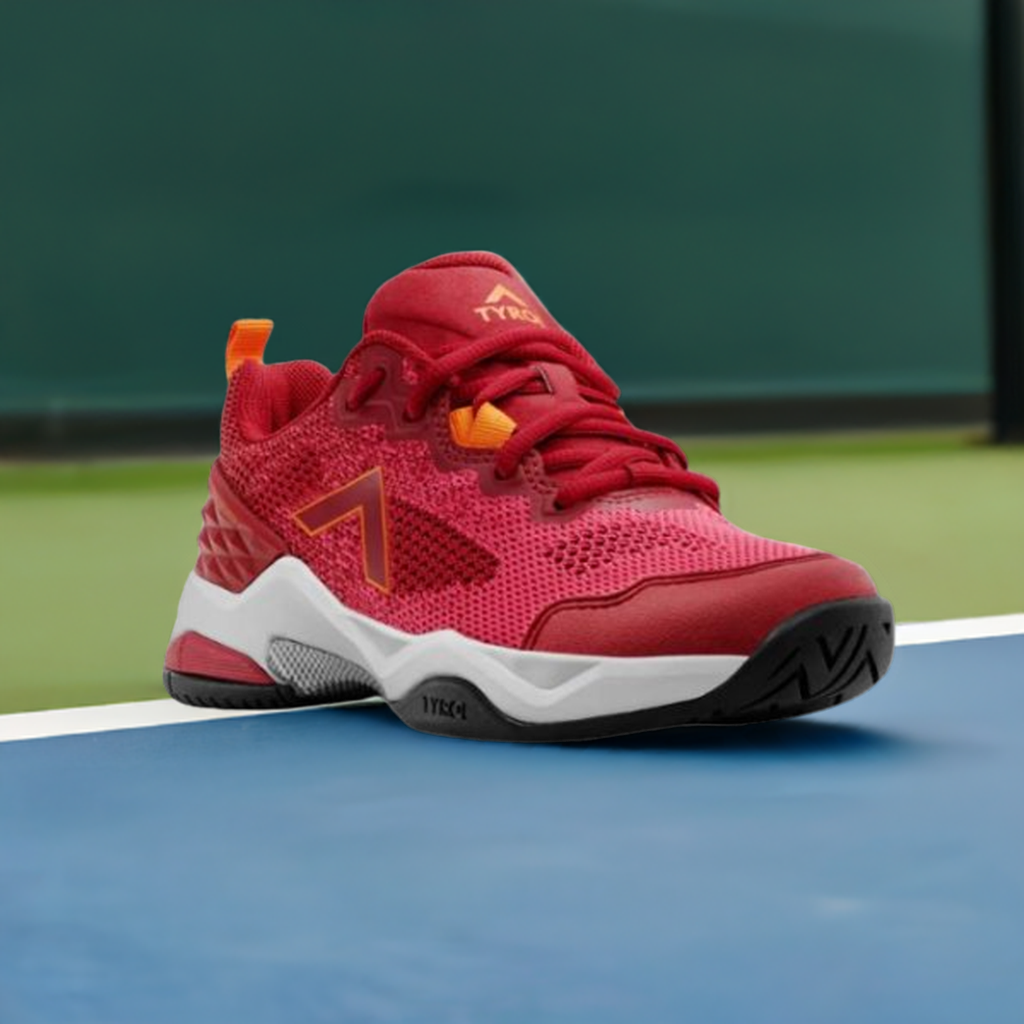 Red athletic shoe on sports court, featuring orange accents, a textured sole, and designed for lateral stability in pickleball.