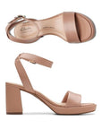 Top and profile view showing Beige ankle strap block heel with silver buckle and single strap across the open toe. Footbbed is light cream color with Clarks logo printed. Outsole is a dark brown rubber 