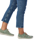 Person wearing jeans and mint Rieker lace-up sneakers.