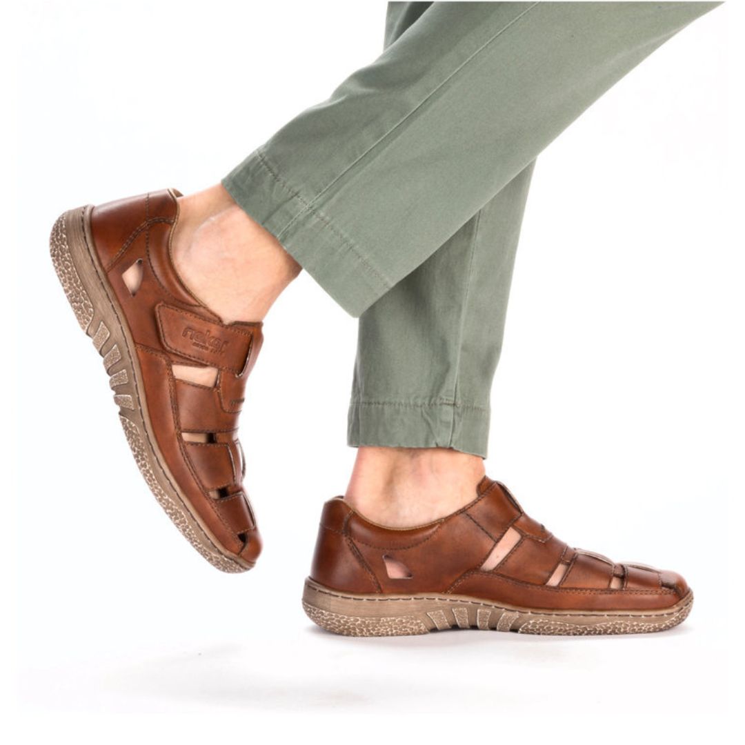 03578 Casual Fisherman Sandal shown in rich brown leather with adjustable Velcro closure, paired with sage green pants. Features breathable cutout design, comfortable rubber sole, and classic fisherman style construction for summer wear.