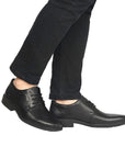 Legs in black jeans wearing black leather dress shoe with bicycle toe.