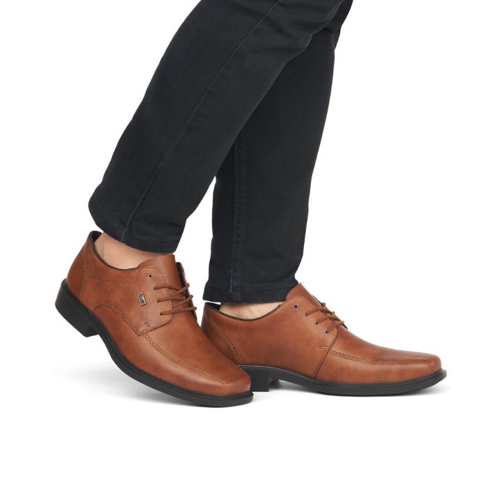 Legs in black jeans wearing brown leather dress shoe with bicycle toe.