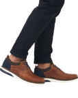 14405 Slip-On Lace Sneaker shown in brown leather with navy blue accents, featuring casual design with clean lines. White rubber outsole visible, sneaker displayed on foot wearing dark jeans, highlighting its everyday versatile style and comfortable fit.