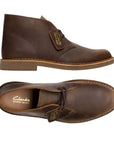 Top and side view of Beeswax brown desert boot with leather tag showing the Clark's logo and Desert Boot name. Dark brown laces, light brown outsole and tan stitching line between upper and outsole