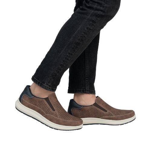 Man in black jeans wearing Rieker brown leather perforated slip on sneakers.