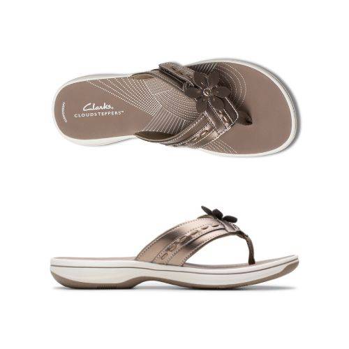 Top and profile view of Bronze thong sandal with white midsole, bronze footbed with white designs including Clarks Cloudsteppers logo, fabric toe post, and adjustable bronze strap with bronze flower. Bronze outsole with rocker bottom design.