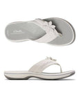 Profile and top view of White thong sandal with white midsole, grey footbed with white designs including Clarks Cloudsteppers logo, fabric toe post, and adjustable white strap with white flower. Dark grey outsole with rocker bottom design.