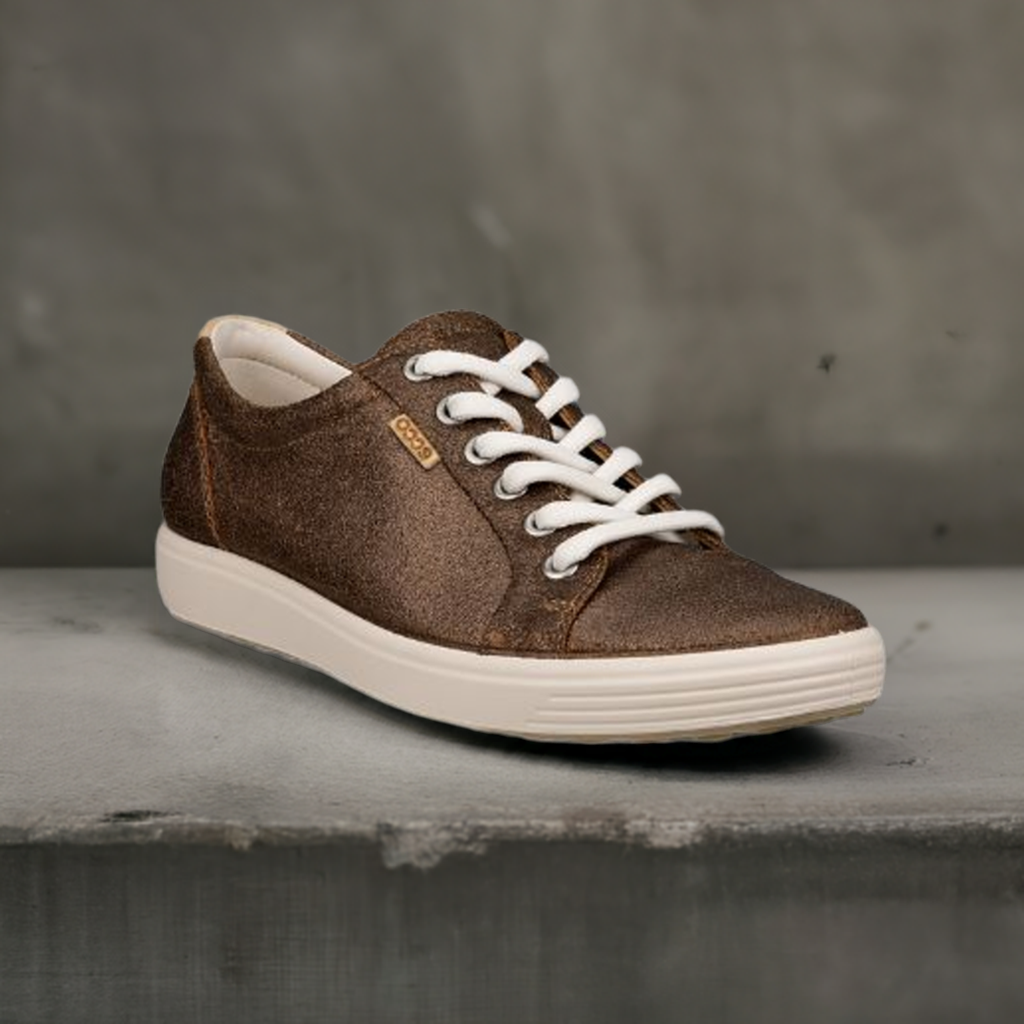 An Ecco bronze textured leather sneaker on a cement block.