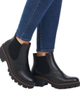 Legs in jeans wearing black leather Chelsea boot with platform outsole.