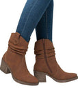 A women in blue jeans wearing brown suede western style boots.