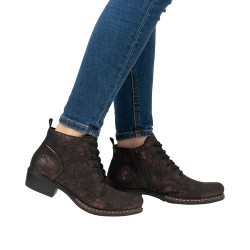 Women in blue jeans wearing black with gold dusting laced dress boots.