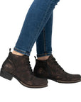 Women in blue jeans wearing black with gold dusting laced dress boots.