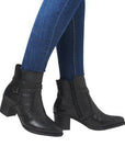 Women in blue jeans wearing black dressier block heel boots with studded ankle straps.