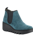 Byne Wedge Bootie in Petrol. A teal suede upper with black elastic goring and a black platform outsole. FLY London logo is embossed near the heel. 