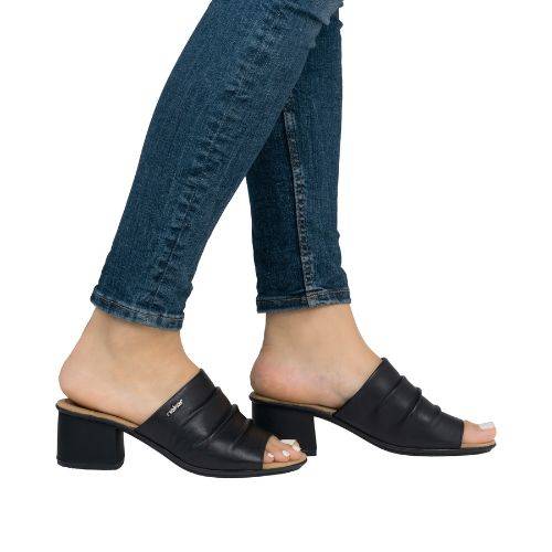 Legs of women wearing blue jeans in the black Rieker block heel slide sandal.