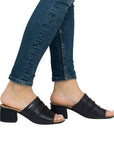 Legs of women wearing blue jeans in the black Rieker block heel slide sandal.