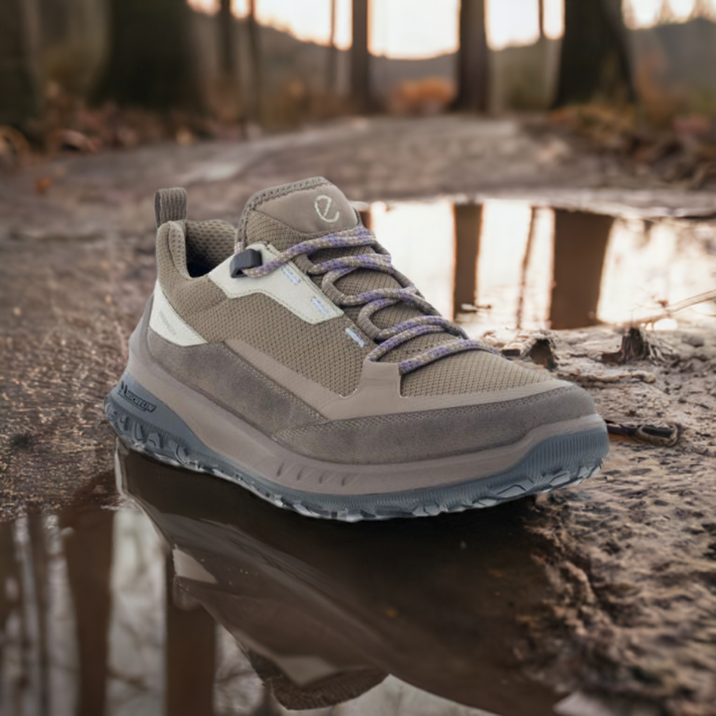 A pair of brown Ecco sneakers with Michelin outsole on a muddy puddle trail.