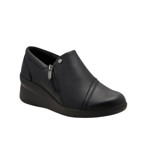 Black leather wedge ankle slip-on shoe. Has a detailed silver button above side zipper. Small detailed diagonal stitching on toe.