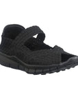 A black Bernie Mev sandal with woven elastic upper,  a peep toe and strap across the top of the foot with a closed in heel, and a rocker bottom black outsole.