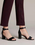 Woman in purple trousers wearing the Deva Mae heeled sandal in black.