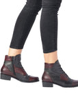 Black jeans wearing multi-colored patchwork ankle boot with lace closure.