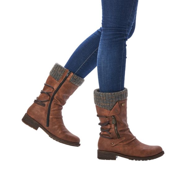 Legs in jeans wearing brown mid-height boot with knitted cuff and decorative outside zipper. Boots also have inside functinoal zipper.