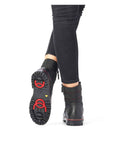 Women wearing black lace-up winter boots. Black rubber outsole with great grip and red collapsible ice cleats