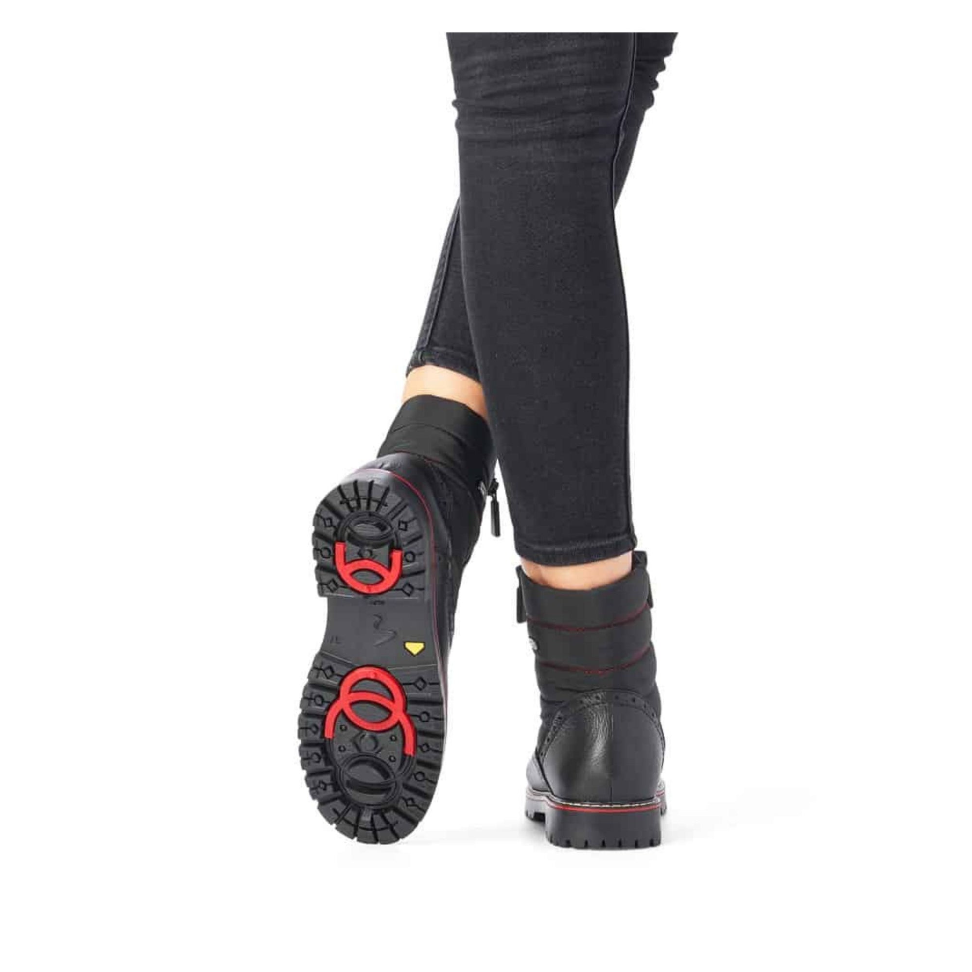 Women wearing black lace-up winter boots. Black rubber outsole with great grip and red collapsible ice cleats