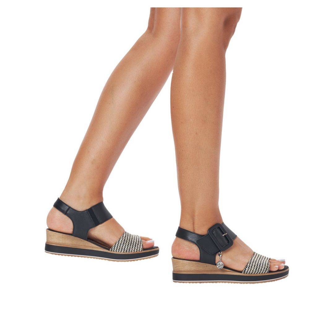 Legs wearing black and white backstrap wedge sandal.