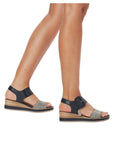 Legs wearing black and white backstrap wedge sandal.