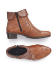 A pair of brown Rieker ankle boots with side zippers on both sides, folded down cuff, detailed stitching, and a low heel.  