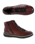 A pair of Rieker red leather sneaker boots with flat black laces, red plaid fabric heel cuff, circle logo on heel,  and black aggressive tread.