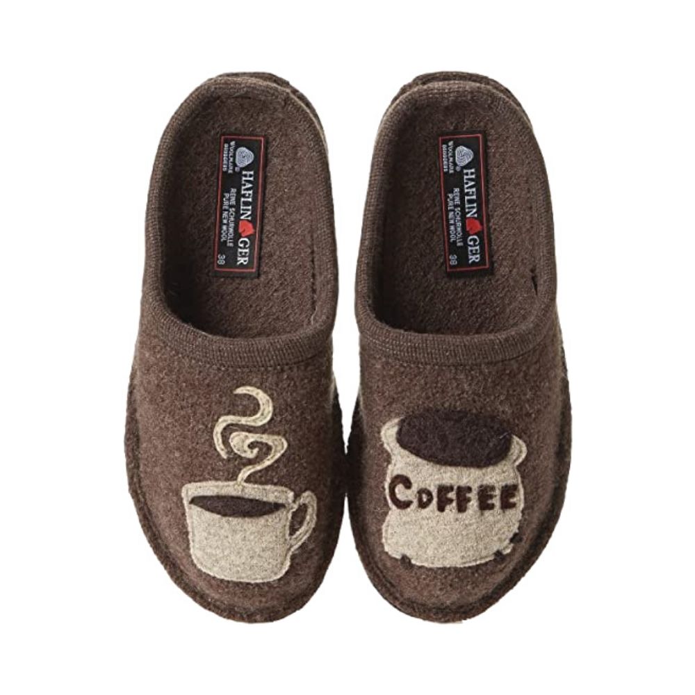 Brown wool open-back slippers. On one foot, there is a felt coffee mug with steam rising out of it, and on the other foot there is a bag of coffee grounds. Haflinger logo is stitched onto the heels. 